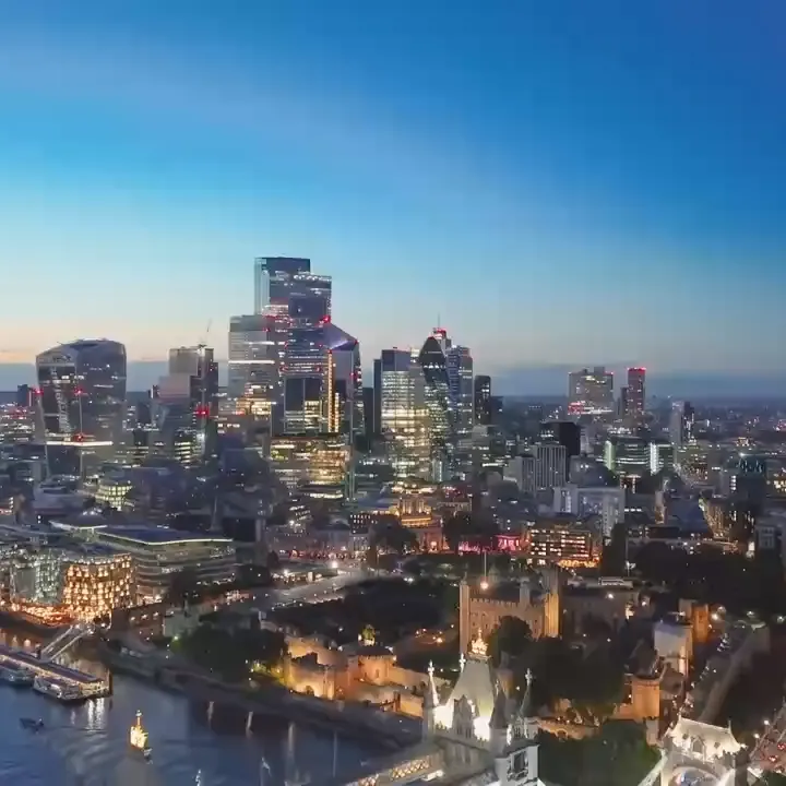 Aerial footage of the City of London at dusk, with Tower Bridge in the foreground and office lights coming on across the skyline