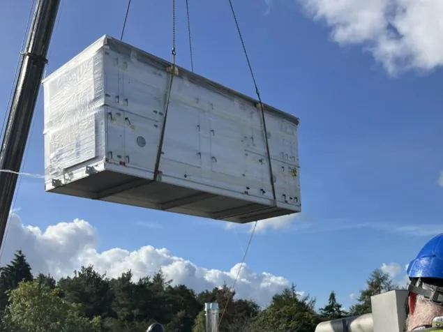 A new, wrapped air handling unit arriving on the roof by crane