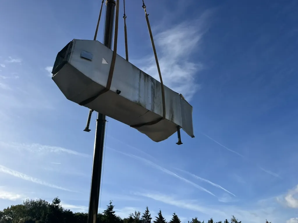 A life-expired air handling unit seen from below as it leaves the roof